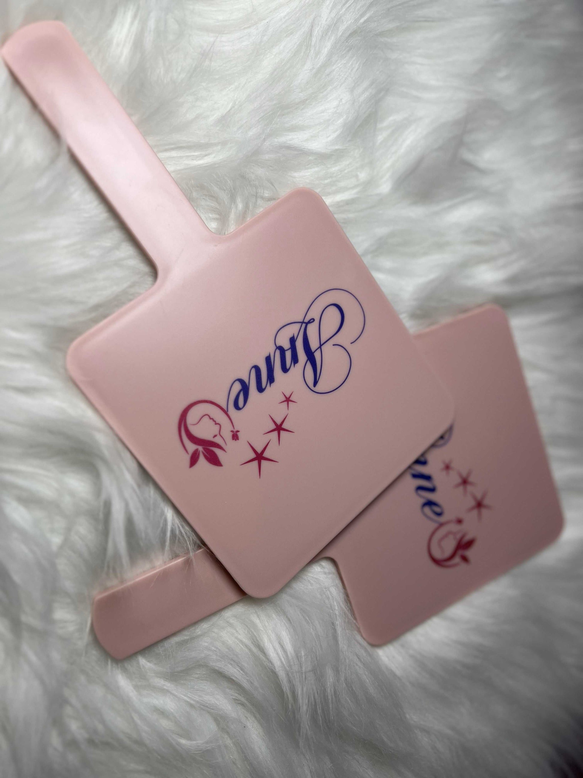 Elegant pink handled makeup mirror with ergonomic grip and stylish square design by Glam Studio
